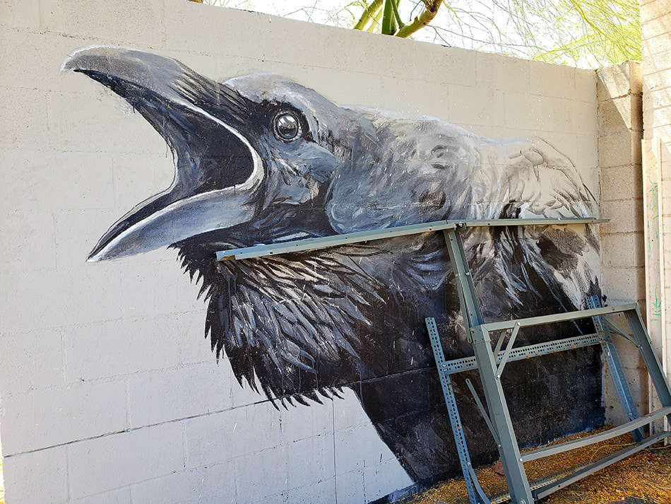 Wheatpaste painting of a raven on an alley way wall