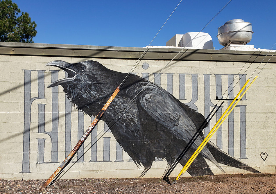 Large painting of a raven with beak open on the back of a building wall